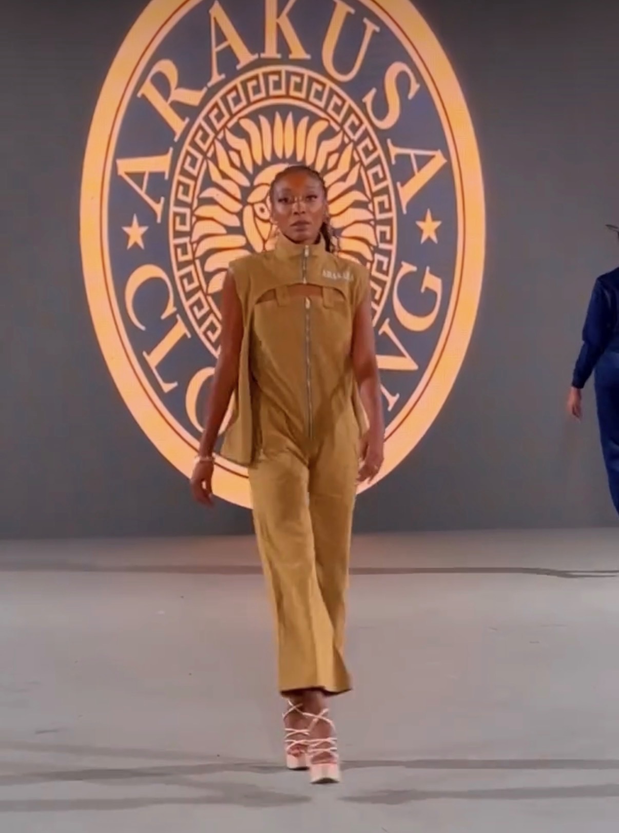 Amari Kelley in a tailored ochre jumpsuit mid-walk
